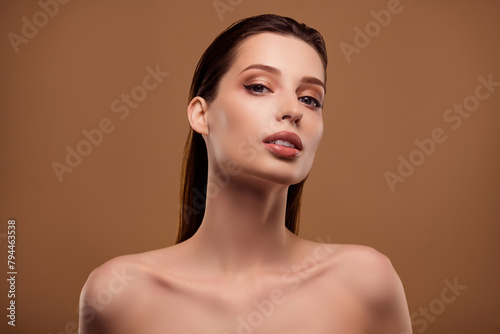 Photo of seductive shiny woman nude shoulders applying maquillage isolated beige color background