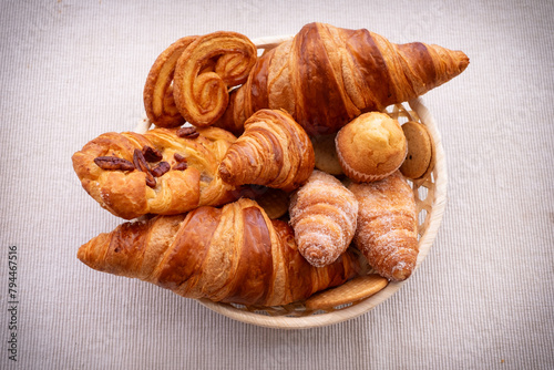Sweet bakery products and croissant in the basket captured from above (top view), white background