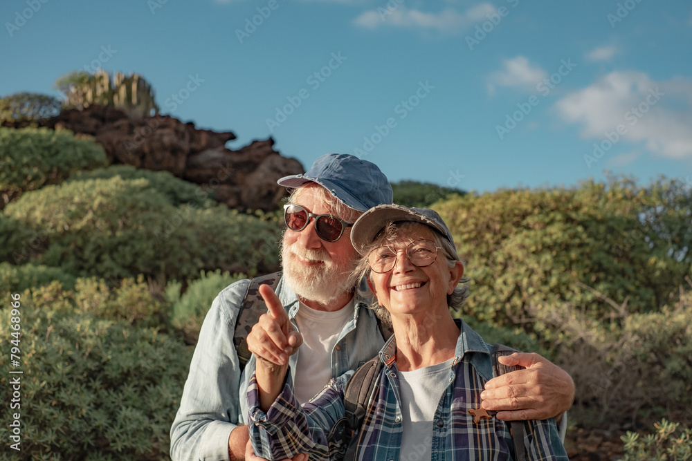 Outdoors activity in nature. Happy caucasian senior couple with backpack enjoying trekking day in countryside admiring landscape, Healthy lifestyle in retirement concept