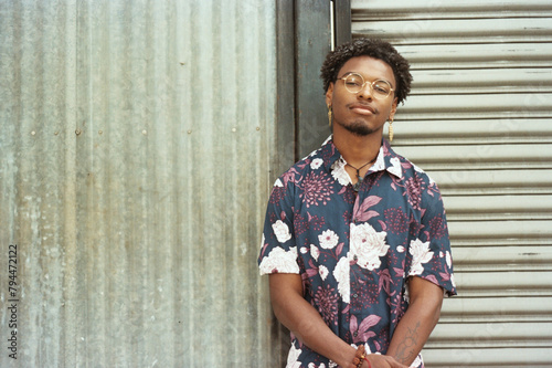 portrait of young black man standing next to wall outside