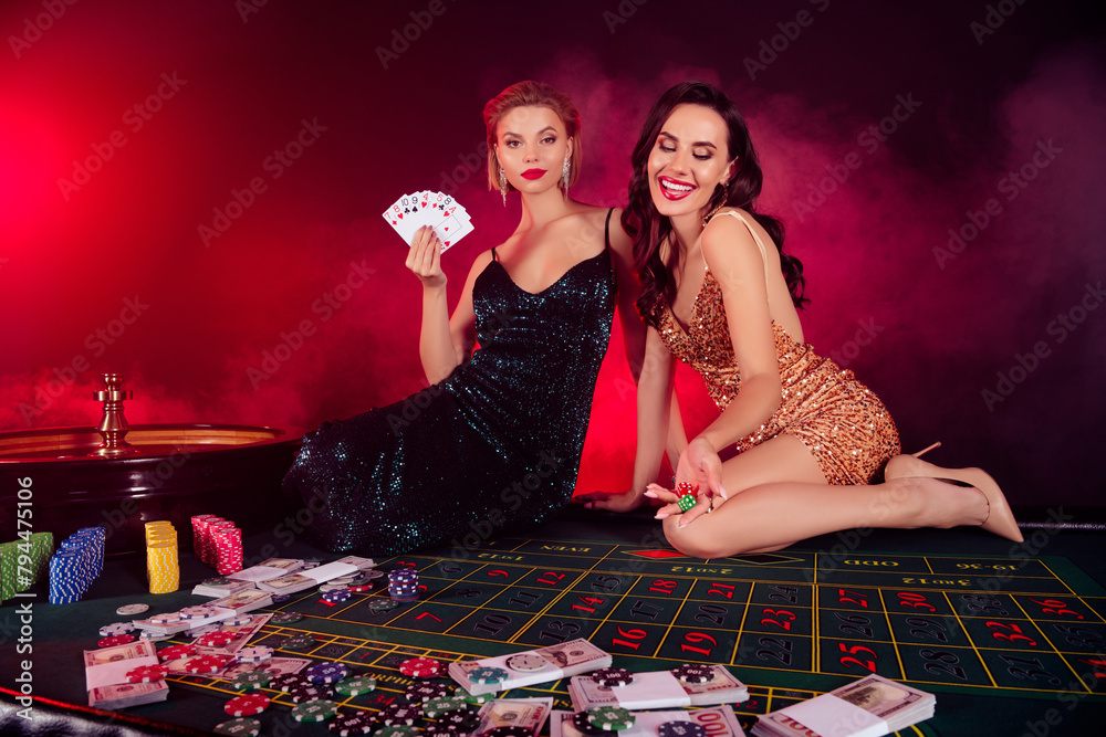 Photo of gorgeous chic people girls sitting poker table throw dice have winning strategy in misty nightclub Photo of gorgeous chic people girls sitting poker table throw dice have winning strategy in misty nightclub