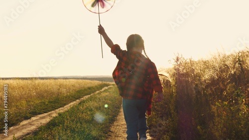 the pinwheel begins to play, child kid runs through park windmill hands, smile face, hand spinning sun, children dream, happy little girl child kid playing with a windmill at sunset, children running