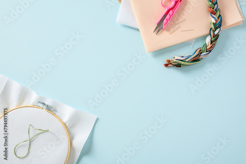 Flat lay composition with cross stitch embroidery and sewing material on blue background photo