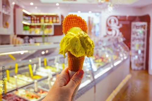 Italian ice - cream cone held in hand on the background of shop in Rome, Italy.It is one of the best ice cream place in town popular among tourists © natalia_maroz