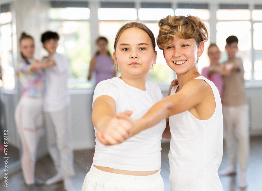Teen girl paired with guy practices movements of waltz dance and trains to perform movements during lesson in choreography studio. Teen girl paired with guy practices movements of waltz dance and trains to perform movements during lesson in choreography studio.