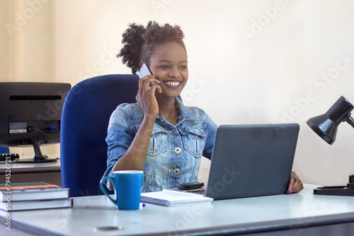 Happy young woman talking on her phone at her desk photo