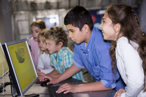 Cheerful interested tweens trying to get out of closed space of escape room stylized under nuclear bunker, using computer