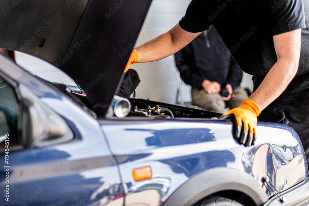 Mechanic and racer, under hood, prepare car for use in Castilla y León garage. Mechanic and racer, under hood, prepare car for use in Castilla y León garage.