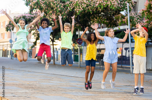 Group of cheerful young girls and boys jumping together. Happy playful kids on long vacation.