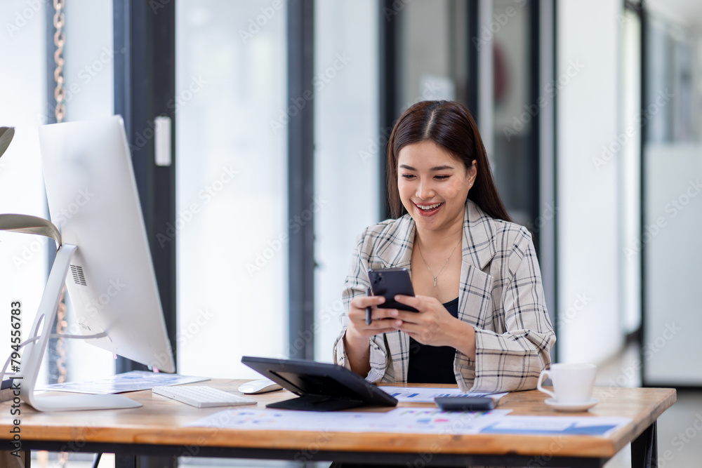 Portrait of young Asian businesswoman in suit, woman smiling and work at workplace inside office, accountant with calculator behind paper phone signing contracts and financial reports Portrait of young Asian businesswoman in suit, woman smiling and work at workplace inside office, accountant with calculator behind paper phone signing contracts and financial reports