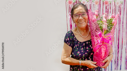 A woman holds a bouquet of flowers and smiles with great happiness. The flowers are pink and arranged in a vase. Concept of  celebration, Mother's Day. copyspace......