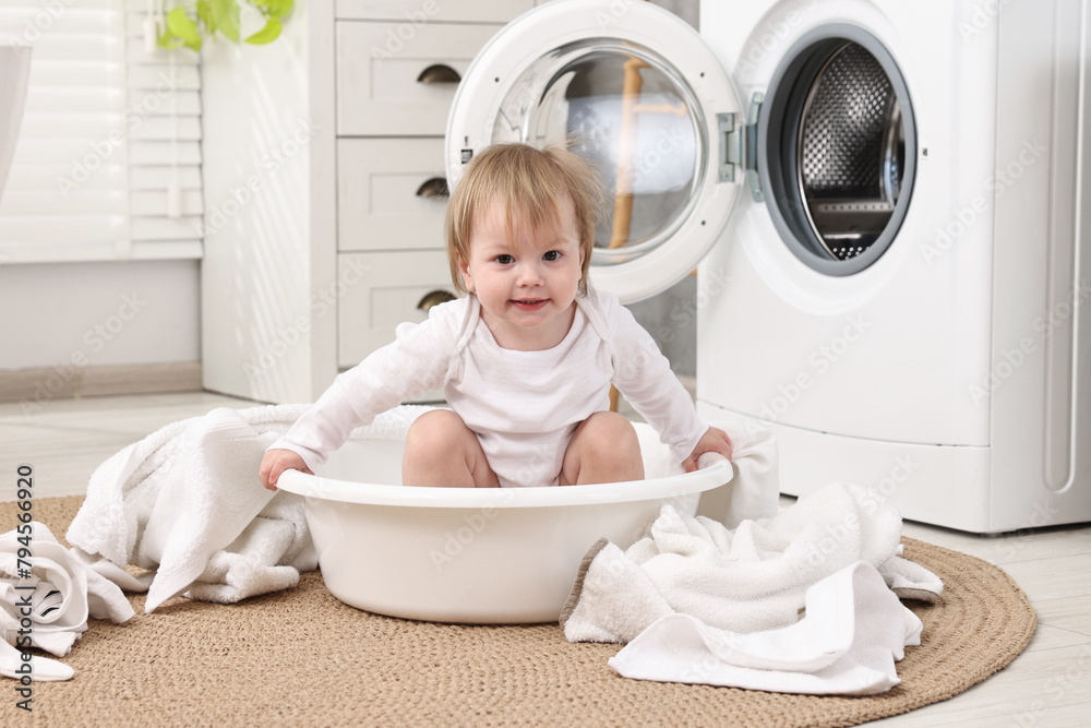 Little girl among baby clothes in bathroom Little girl among baby clothes in bathroom
