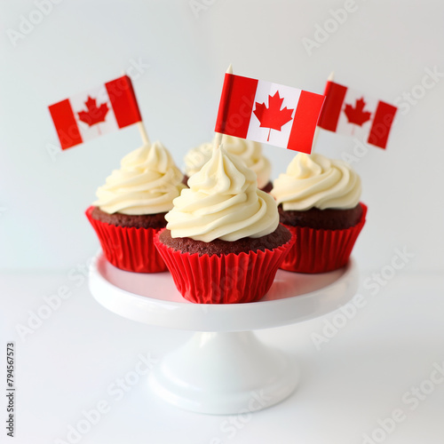 Happy Canada Day celebration cupcakes with red and white maple leaf flag on white cake stand against a white background.