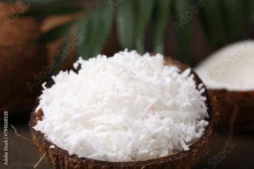 Coconut flakes in nut shell on table, closeup