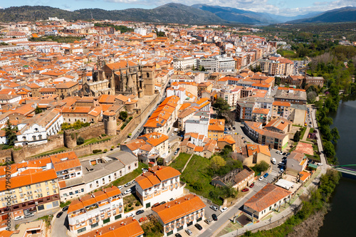 Picturesque aerial view of Plasencia city located in valley of Jerte river overlooking terracotta tiled roofs of residential buildings and medieval cathedral complex in spring, Extremadura, Spain