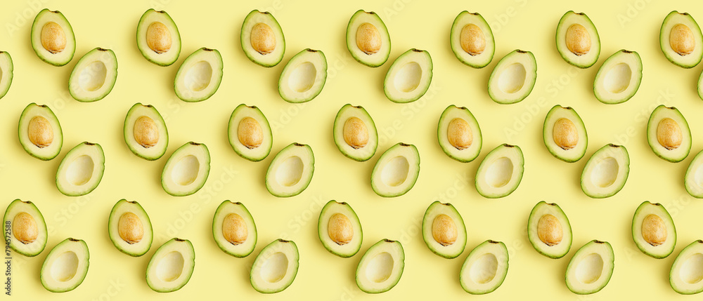 Many halves of fresh ripe avocados on yellow background. Pattern for design Many halves of fresh ripe avocados on yellow background. Pattern for design