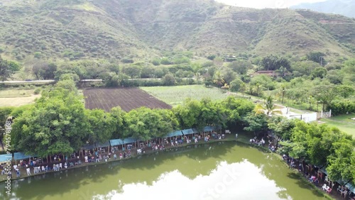 People fishing in a beautiful lake. A green and sunny landscape surrounded by lots of nature.