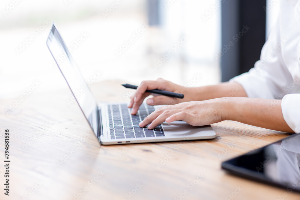 Closeup of hands typing on a laptop keyboard, Freelancer working on laptop at desk in loft office Closeup of hands typing on a laptop keyboard, Freelancer working on laptop at desk in loft office
