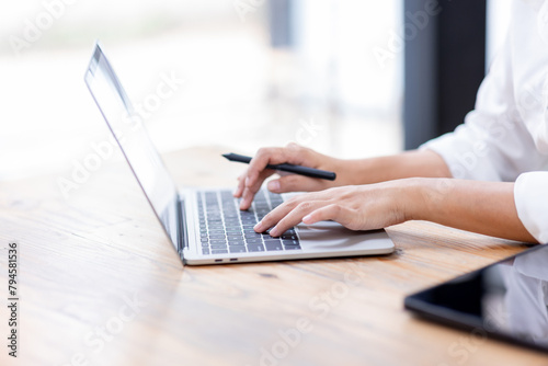 Closeup of hands typing on a laptop keyboard, Freelancer working on laptop at desk in loft office