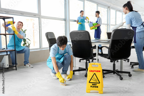 Team of young janitors cleaning in office
