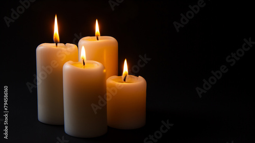Four lit candles in the dark, glowing with a tranquil and serene light.
