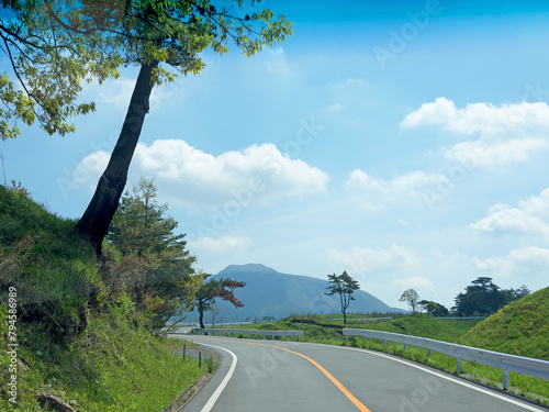 Travelling on Kyushu, driving to Mt Aso by lonely road with lush green grass on roadsides on sunny day