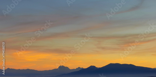 Luminoso tramonto arancio e ocra sopra le montagne italiane