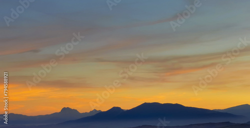 Luminoso tramonto arancio e ocra sopra le montagne italiane photo