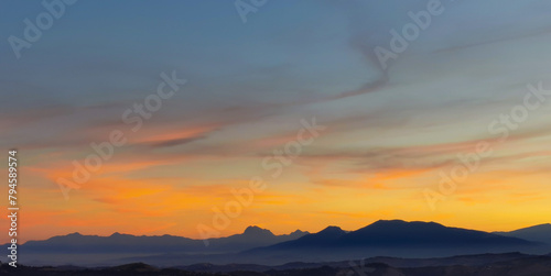 Luminoso tramonto arancio e ocra sopra le montagne italiane