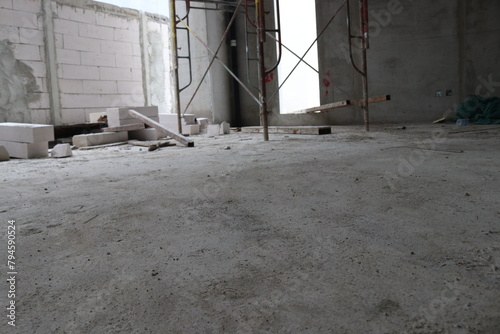 Photo of a wall being built with bricks arranged and mixed with cement and scaffolding in a building under construction