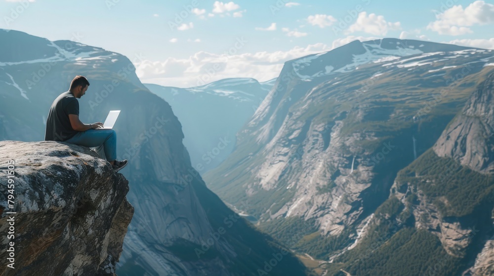 An individual perched on a high mountain ledge, typing away on their laptop, the sprawling valley below offering a breathtaking backdrop to their remote work setup.