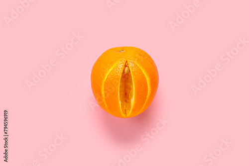 Fresh cut orange on pink background. Sex education photo