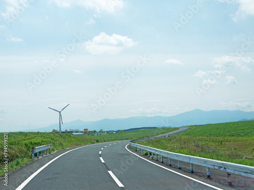 Travelling on rural Kyushu, driving to distant Mount Aso volcano caldera by lonely road through the green valley with wind turbine on sunny day photo