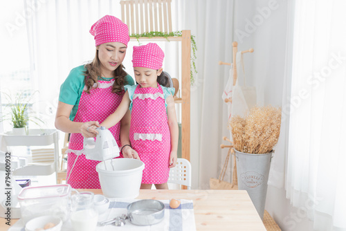 asian female and asian children use electric dough mixer in kitchen room, bakery learning activity, they cooking homemade bakery and feeling happy