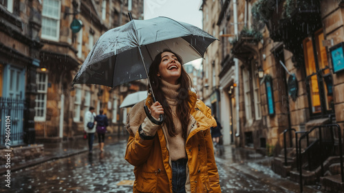 Young tourist woman enjoys the rain with an umbrella raised in the streets of Scottish Capital Edinburgh