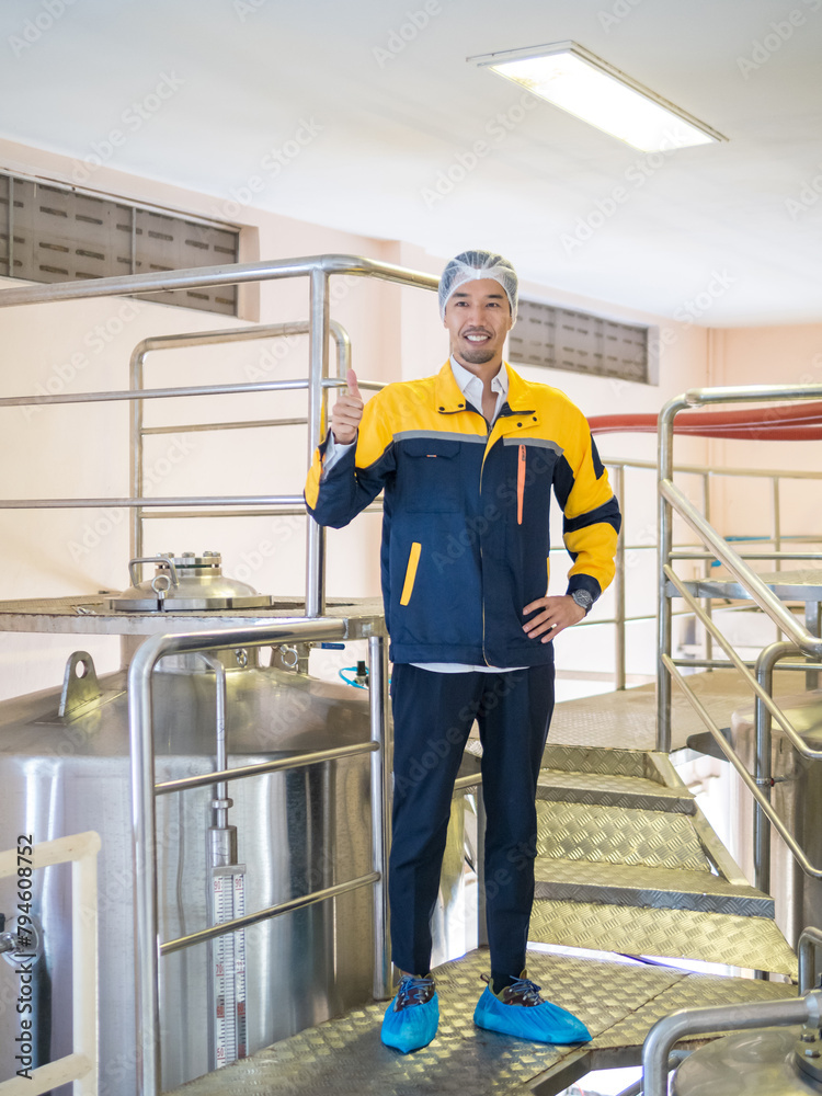Engineer technicians staff man one person smiling and inspect check safety quality control working job in beverages vats barrels on modern technology water factory machine industry plant in warehouse.