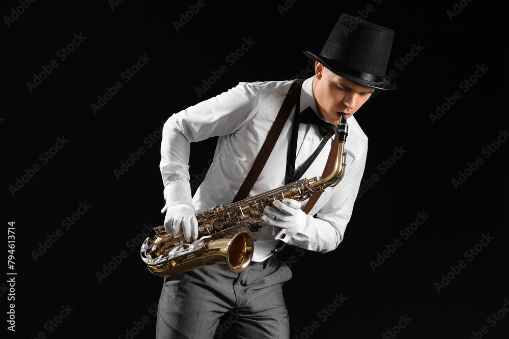 Naklejka premium Male artist playing saxophone on black background