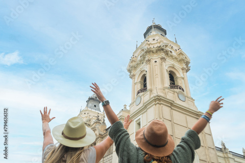 tourists raise their arms in front of lima's cathedral. Copy space