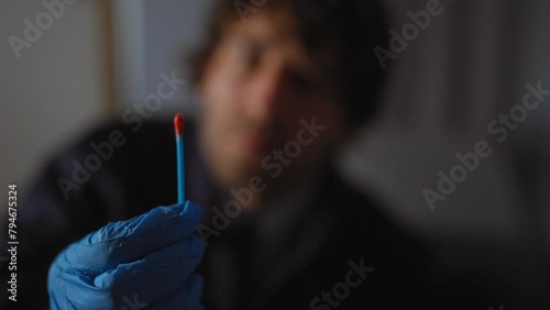 Focused man in suit inspecting evidence with glove in a dimly lit indoor investigation setting. photo