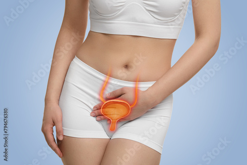 Woman suffering from cystitis on light blue background, closeup. Illustration of urinary system © New Africa