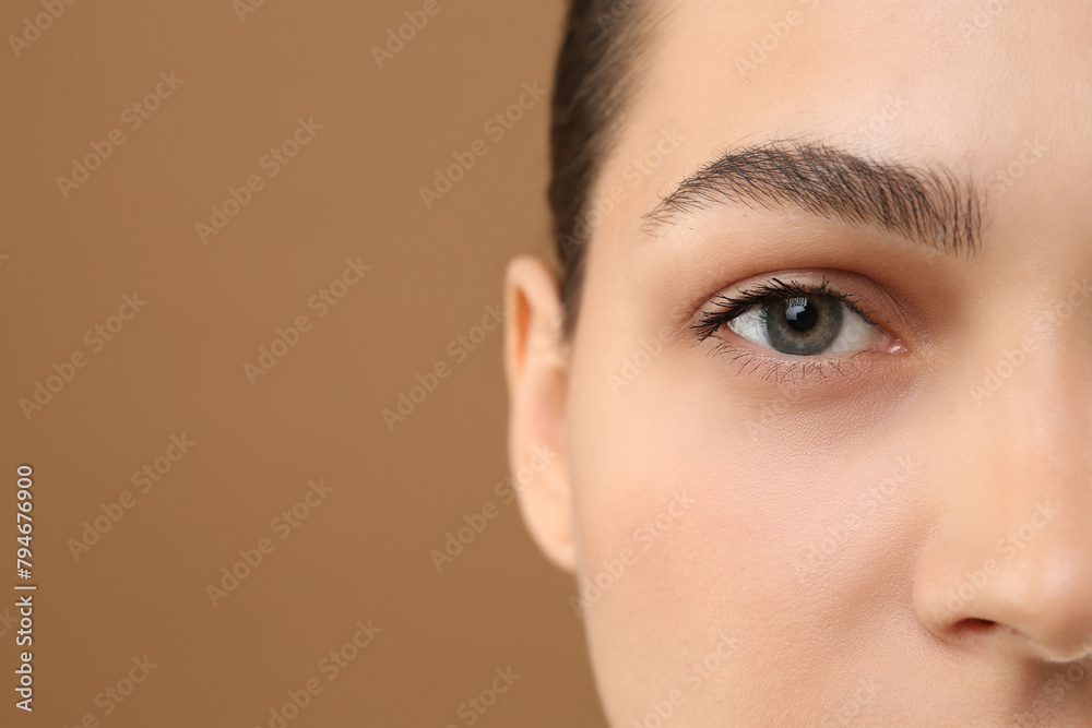 Young woman with perfect eyebrows on brown background, closeup. Space for text Young woman with perfect eyebrows on brown background, closeup. Space for text