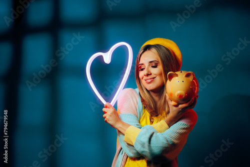 Woman Holding a Neon Heart and a Piggy Bank. Happy girl making amends between personal and professional live 
 photo