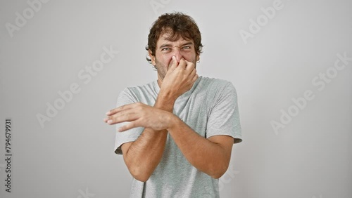 Shocked young man in t-shirt holding his nose in disgust - stinky, intolerable bad smell; an offensive stench over white isolated background photo