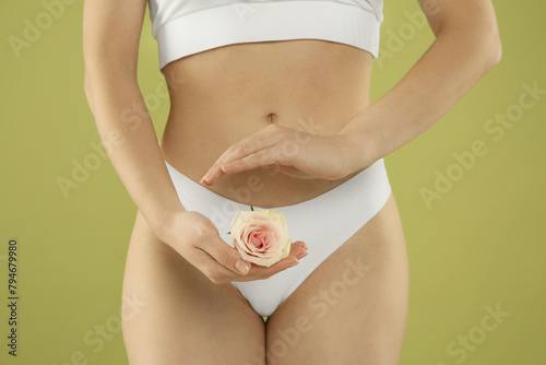 Gynecology. Woman in underwear with rose flower on green background, closeup