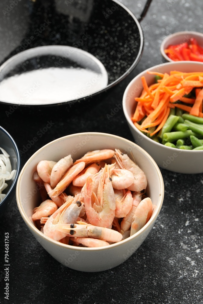Shrimps, vegetables and black wok on grey textured table, closeup Shrimps, vegetables and black wok on grey textured table, closeup