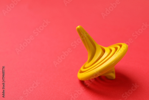 One yellow spinning top on red background  closeup. Space for text