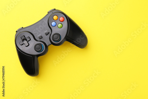 Wireless game controller on yellow background, top view. Space for text