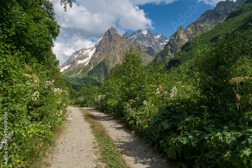 View of the Dombay-Ulgen gorge in the mountains of the North Caucasus and the trail to the Chuchkhur waterfall near the village of Dombay on a sunny summer day, Karachay-Cherkessia, Russia photo