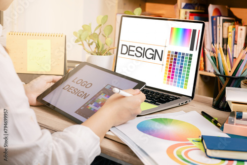 Designer at work on a table, selecting color shades for creative graphic design with laptop and tablet