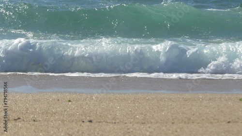 Waves breaking on sandy beach. Low angle, shallow depth of field.